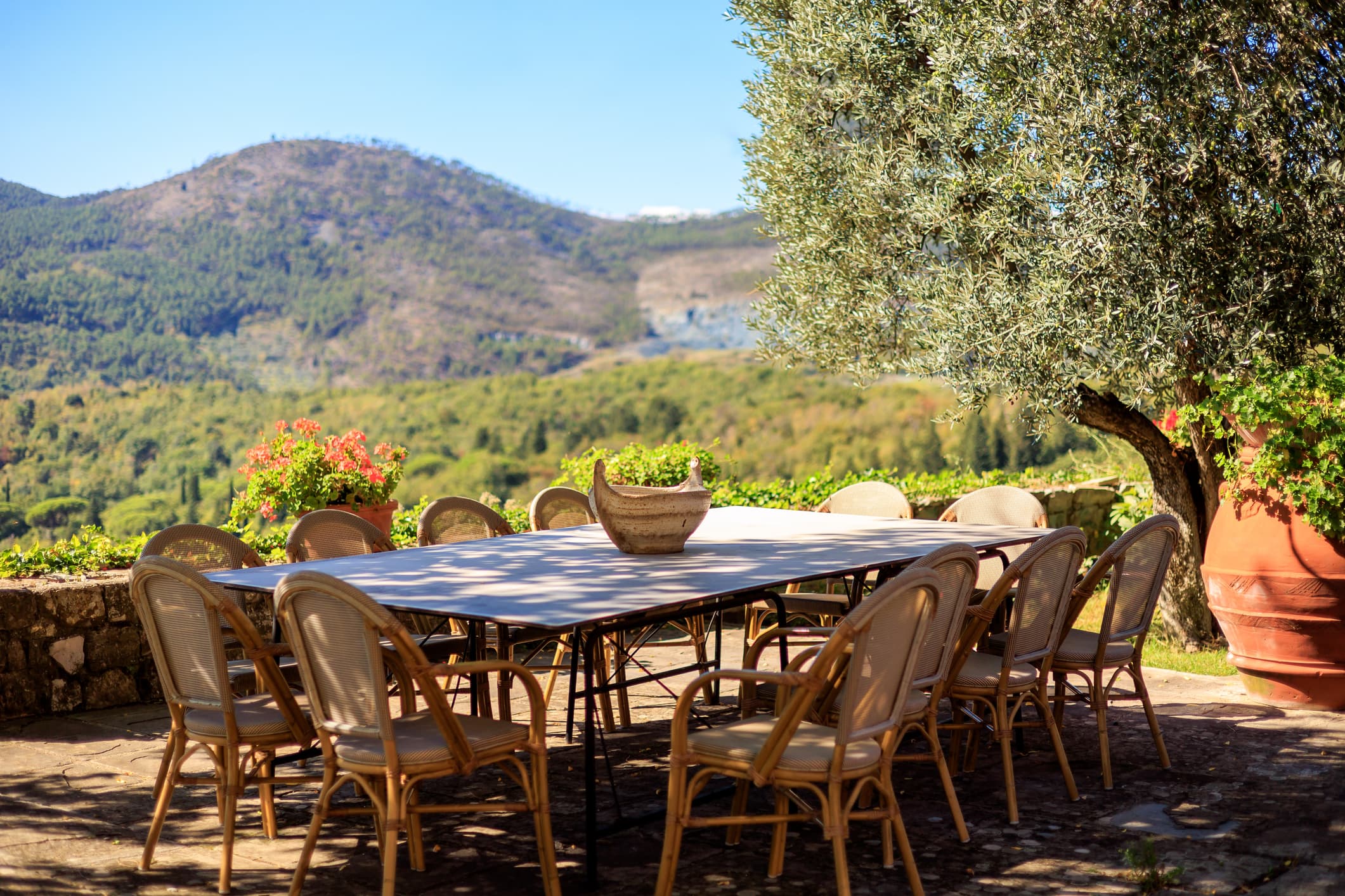 Long shaded table set for a group dinner on a villa terrace